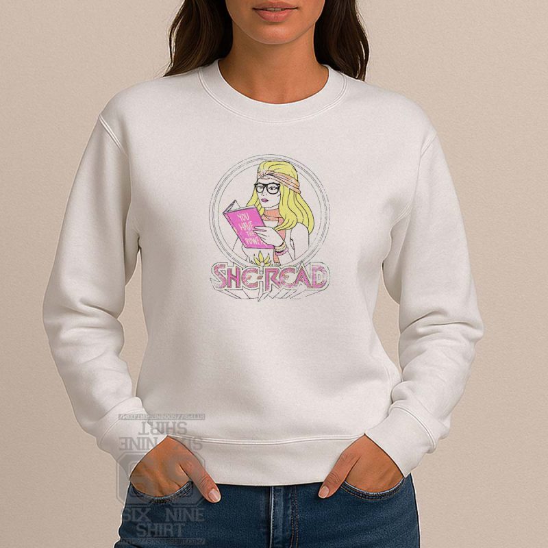 Illustrated “She-Read” design of a retro blonde woman reading a book titled “You Have the Power” in pink, feminist and book-themed apparel