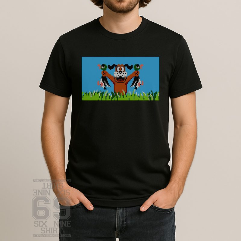 Retro video game style shirt featuring a pixel art dog proudly holding a duck, referencing a classic 1980s shooting game, on a black tee.
